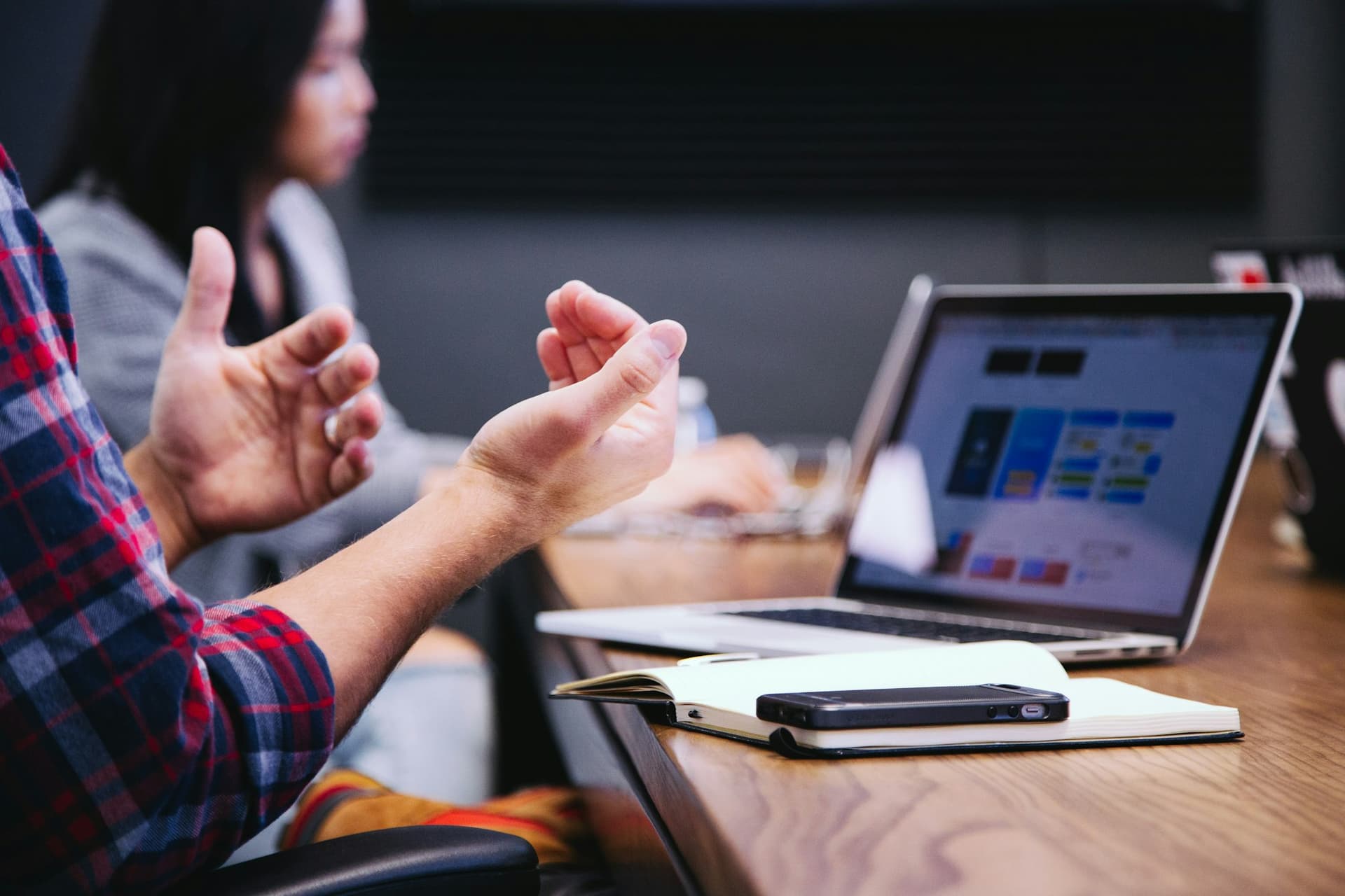 Hands gesturing during a discussion beside a laptop