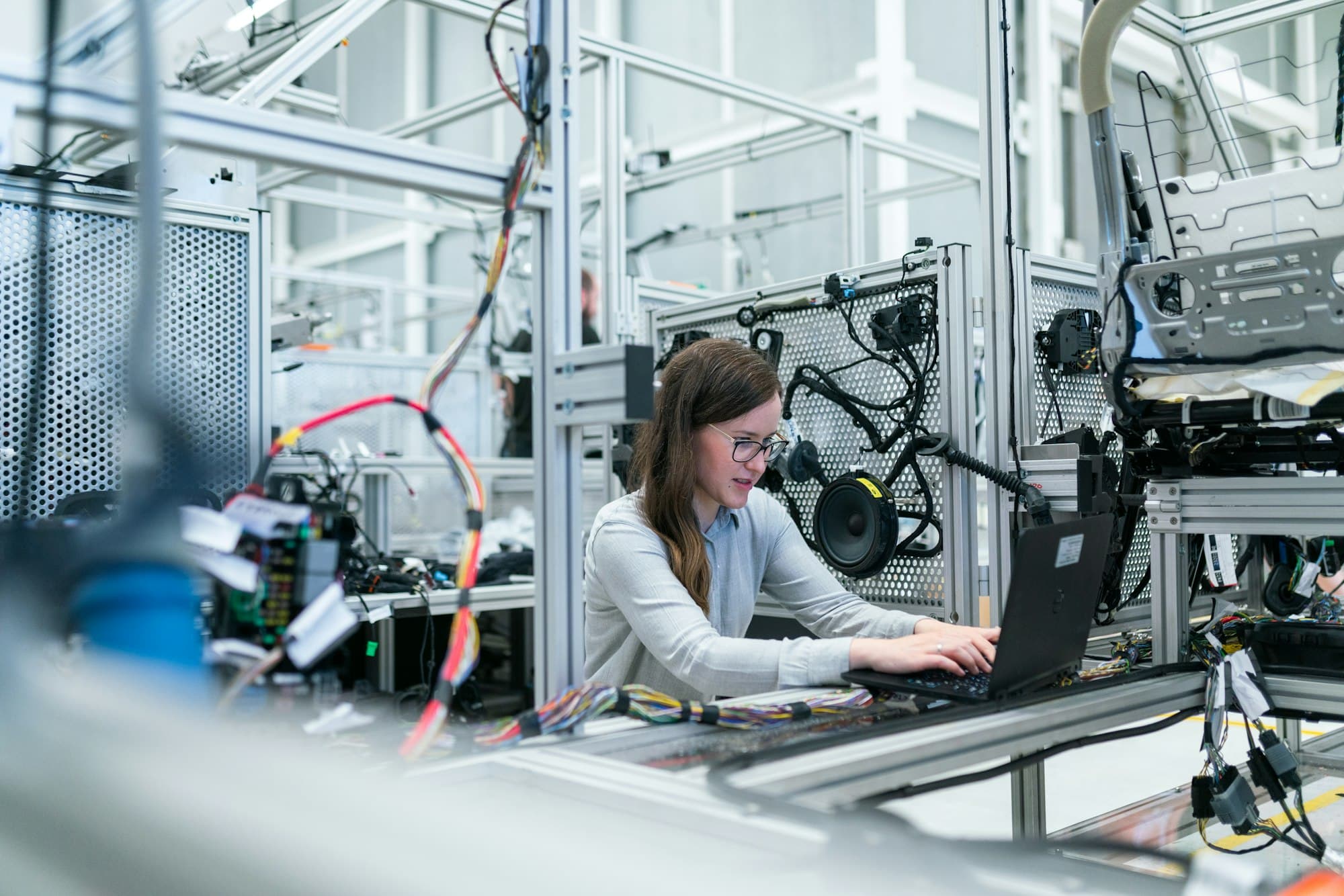 Engineer working at a laptop beside automated factory equipment