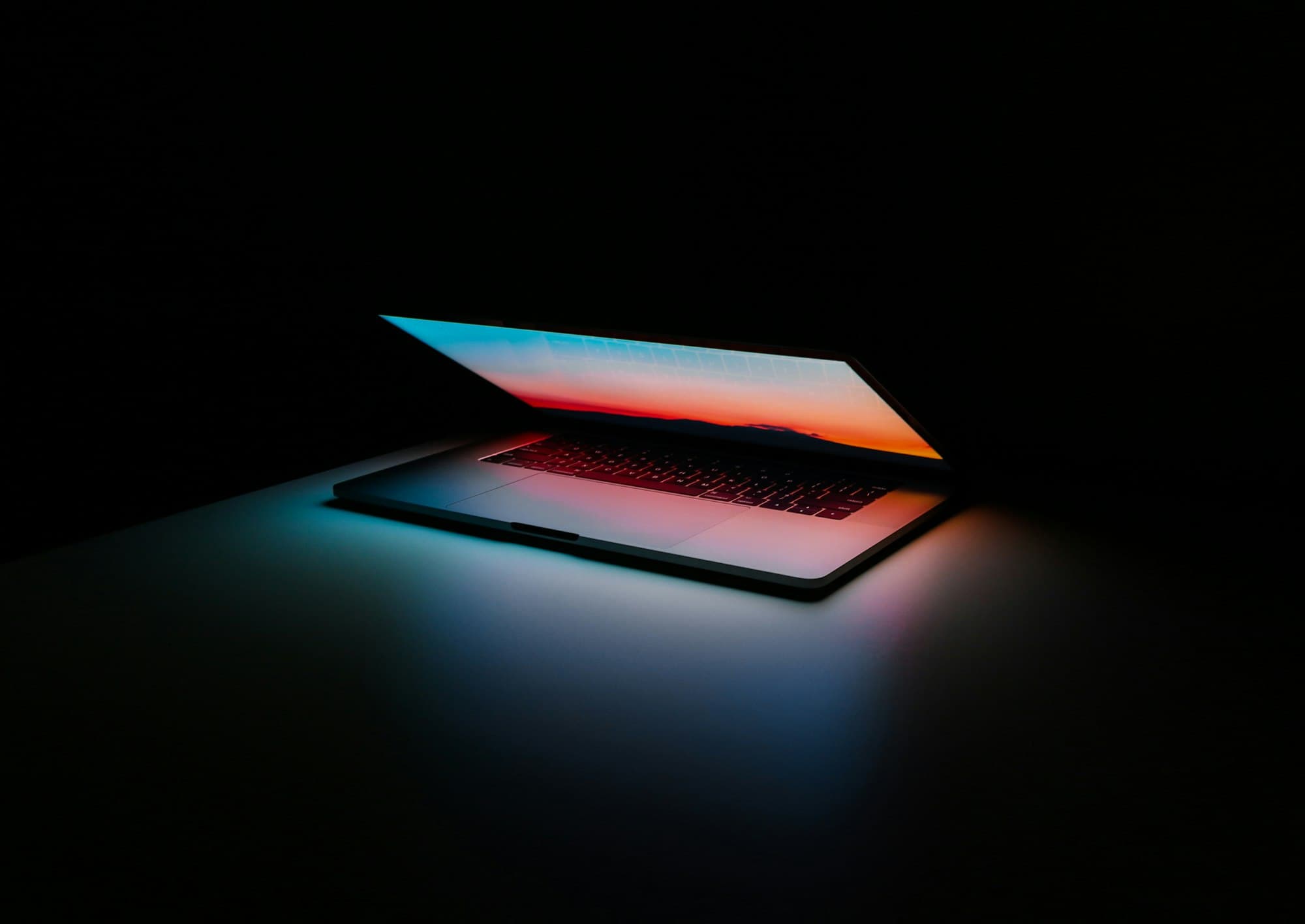 Half-open laptop glowing in a dark room